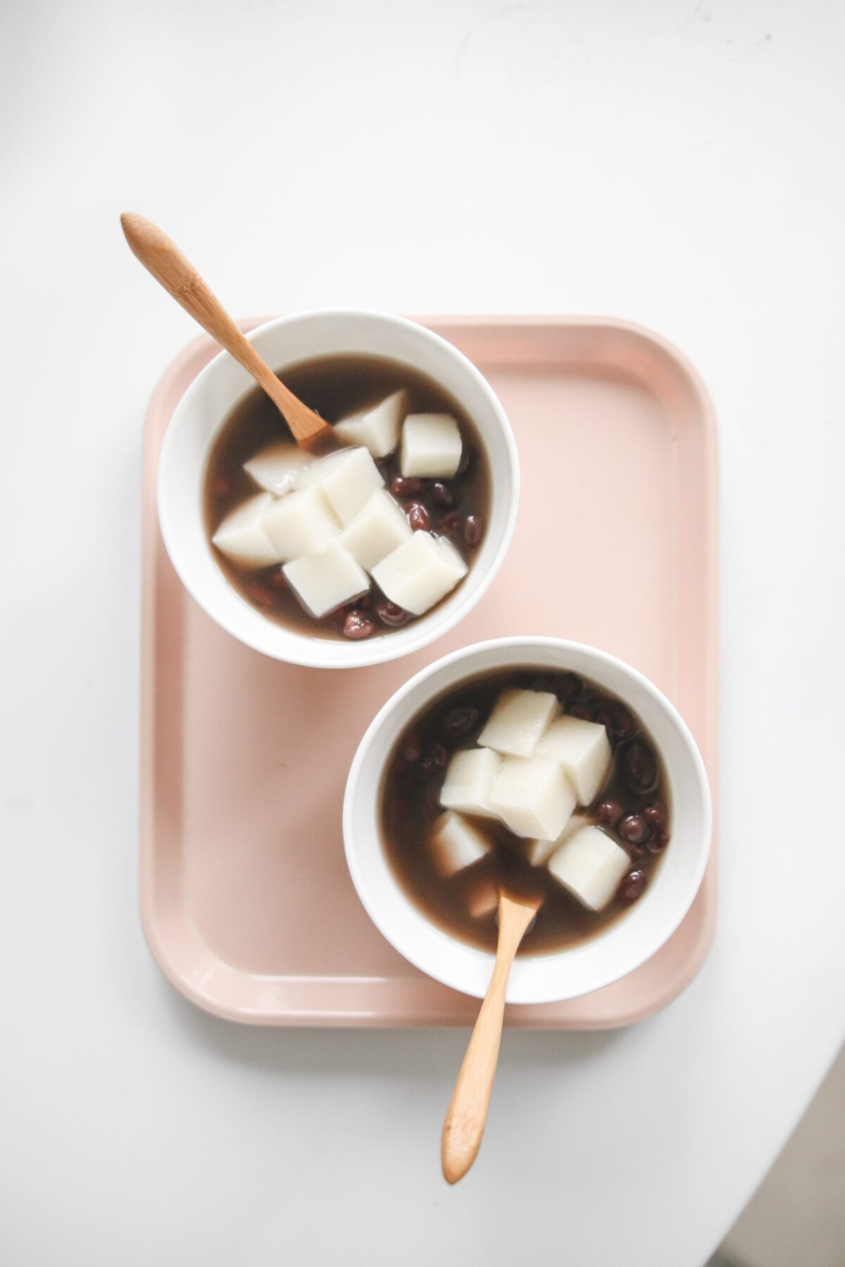 two bowls of Japanese red bean soup topped with mochi with wooden spoons resting on the side. 