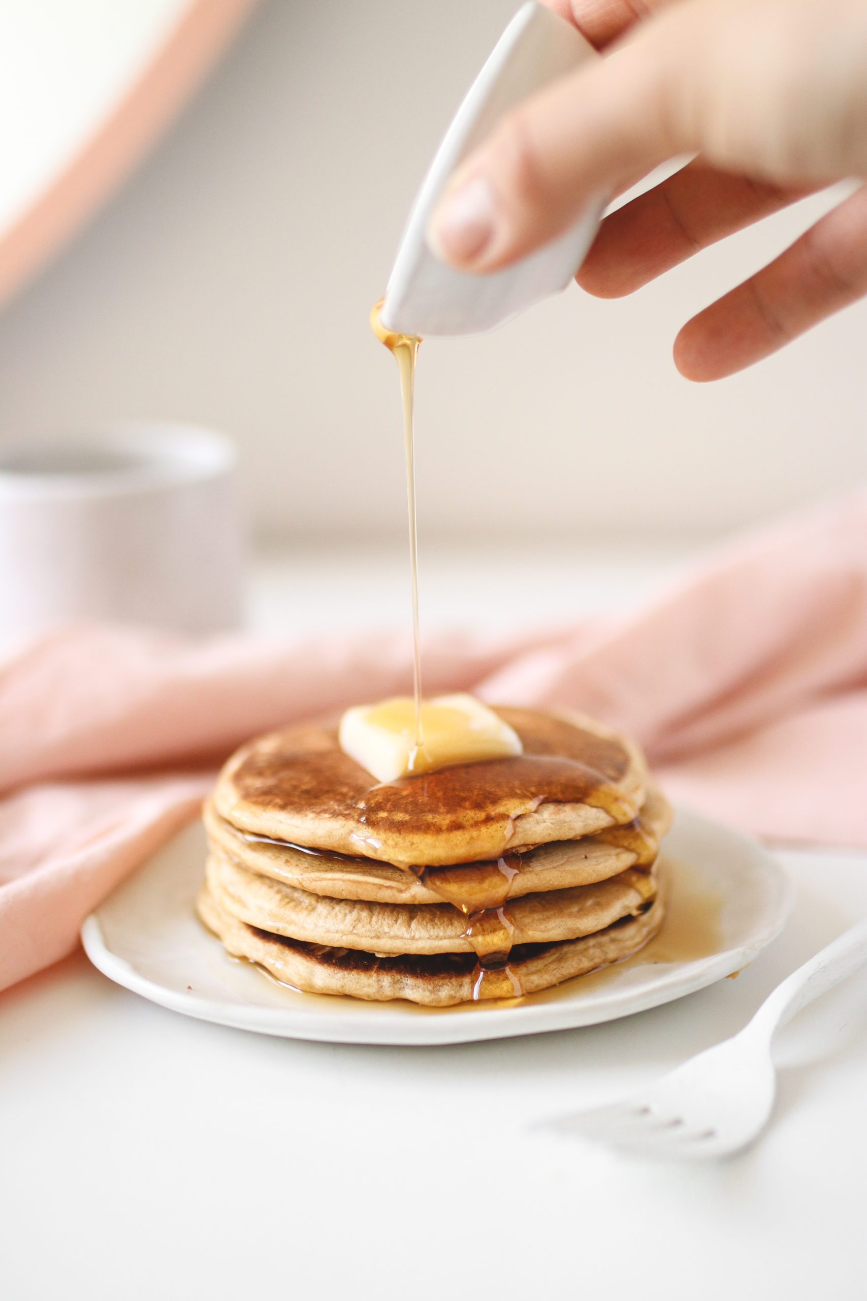 a hand pouring syrup over a stack of chickpea flour pancakes.