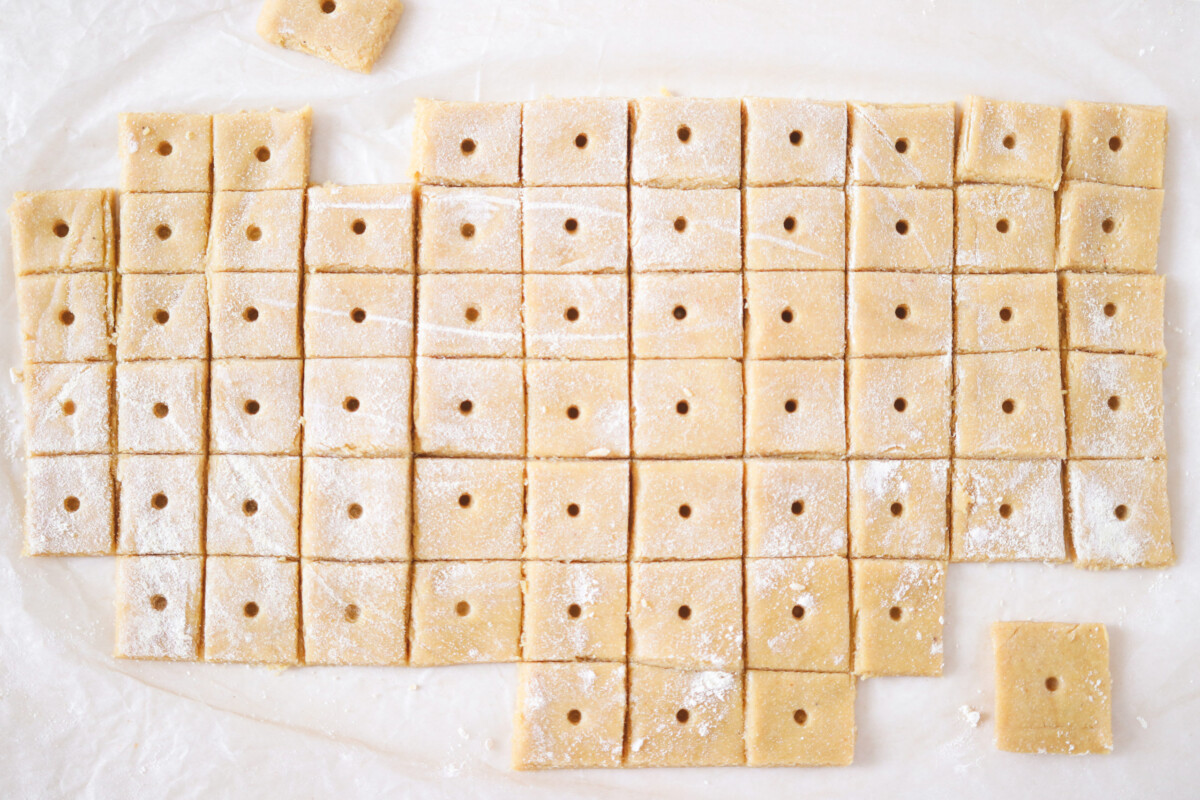 raw dough sliced into squares with a hole in the middle.
