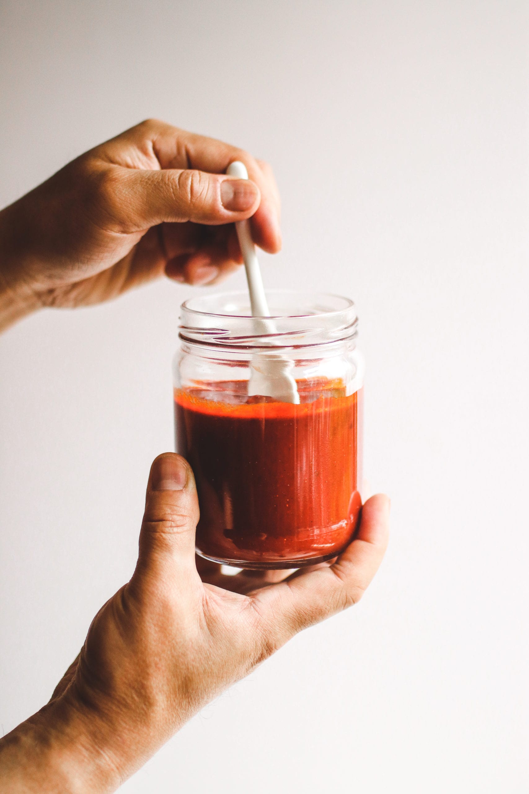 a hand mixing Korean chili paste in a glass jar