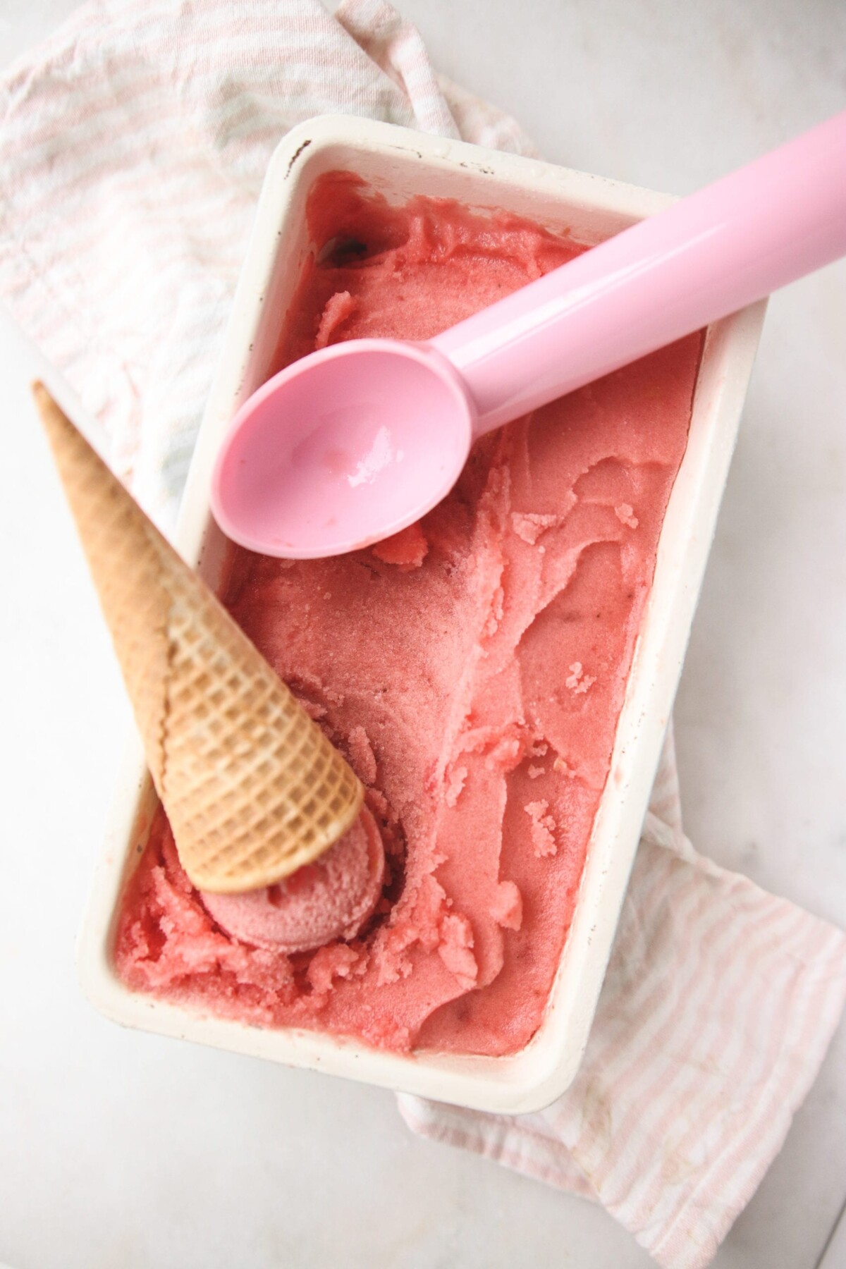 a white dish filled with sugar free sorbet with a pink scooper resting on top
