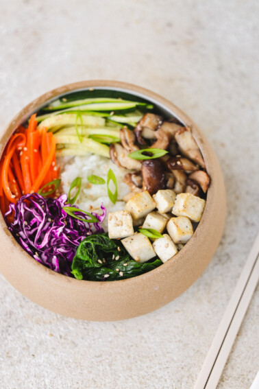 an overhead shot of veggies, rice, and tofu in a bowl