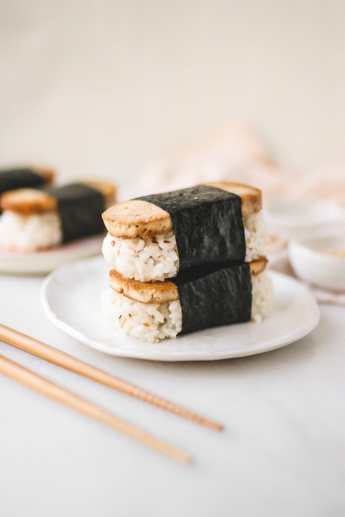 two Hawaiian musubi's stacked on top of each other on a white plate