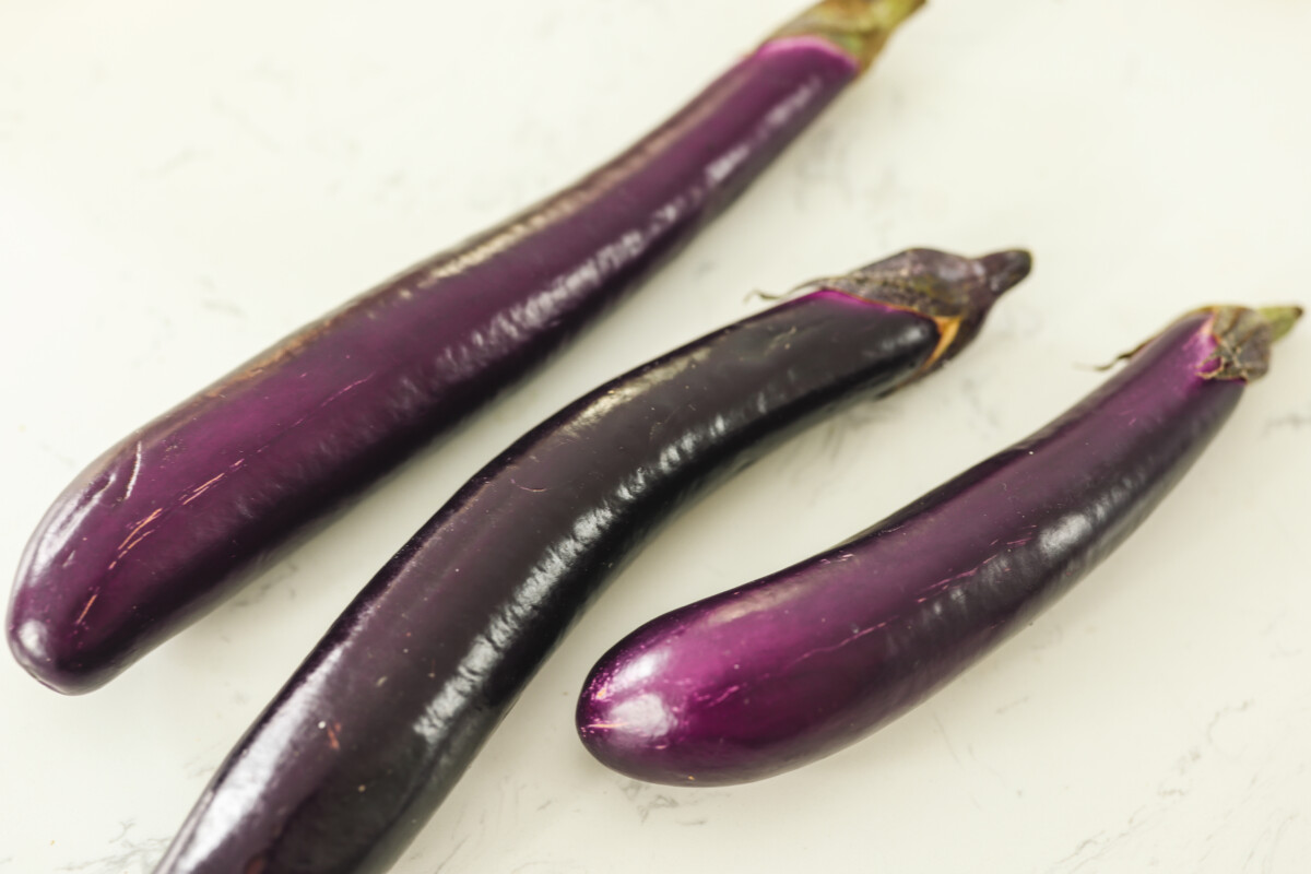 three eggplants on a white surface. 