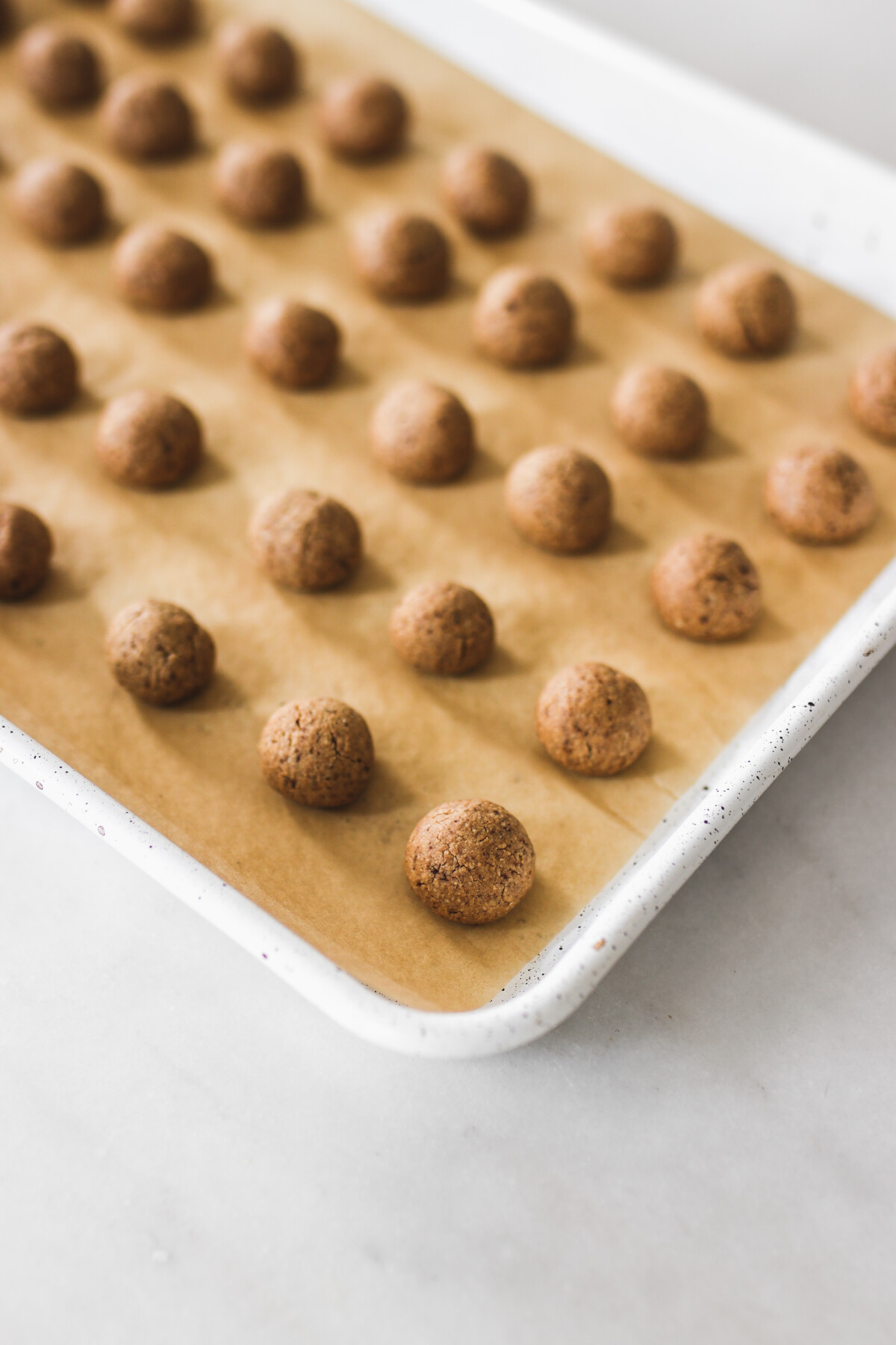 raw cookie dough balls on a lined baking sheet