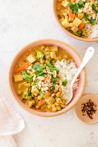 peanut curry over white rice in a bowl and topped with garnish