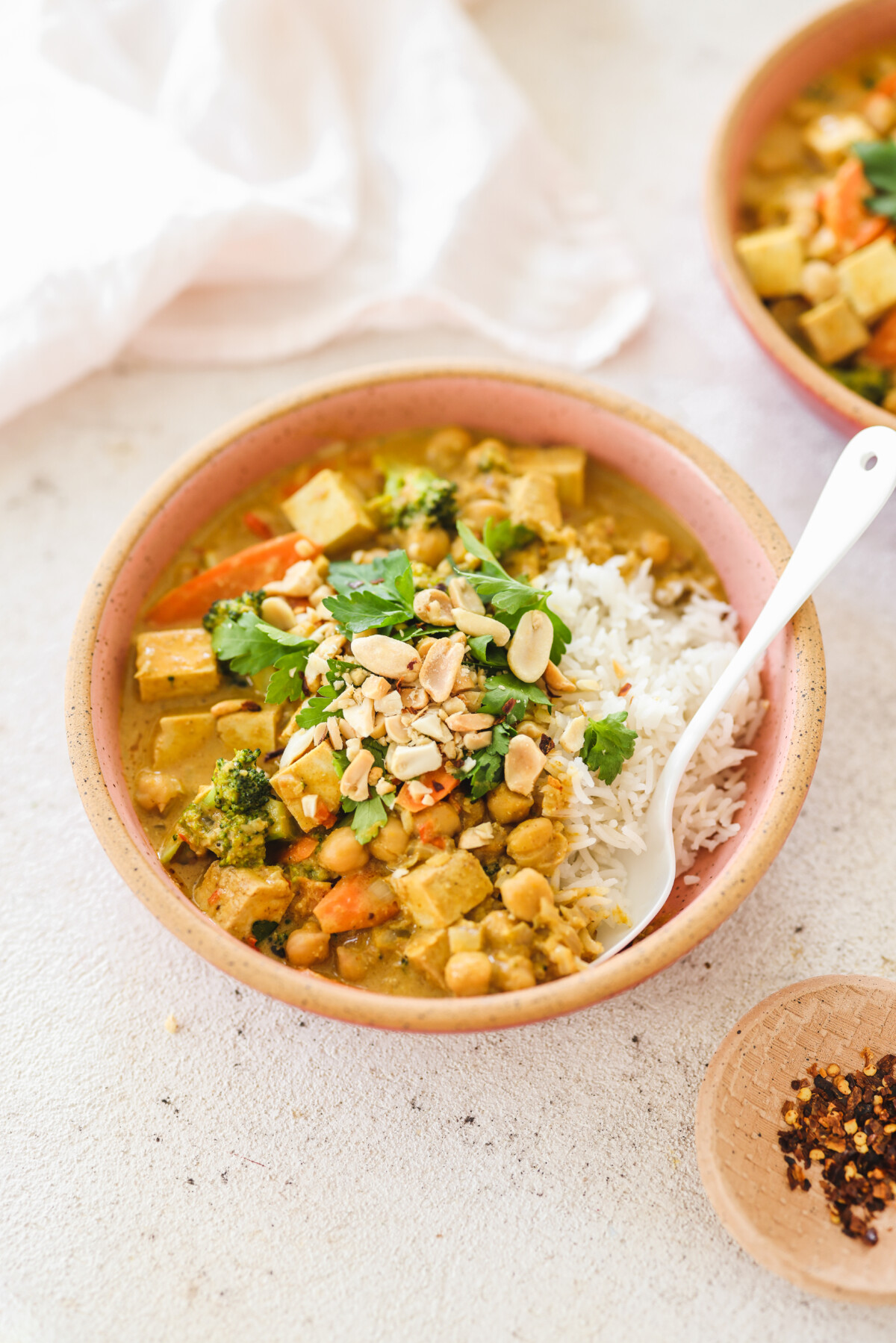 a bowl of peanut curry served over rice and topped with cilantro and crushed peanuts. 
