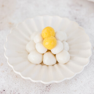 a plate with white glutinous rice balls in a pyramid with two orange balls on top.
