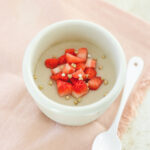 a white bowl filled with vegan pudding and topped with strawberries