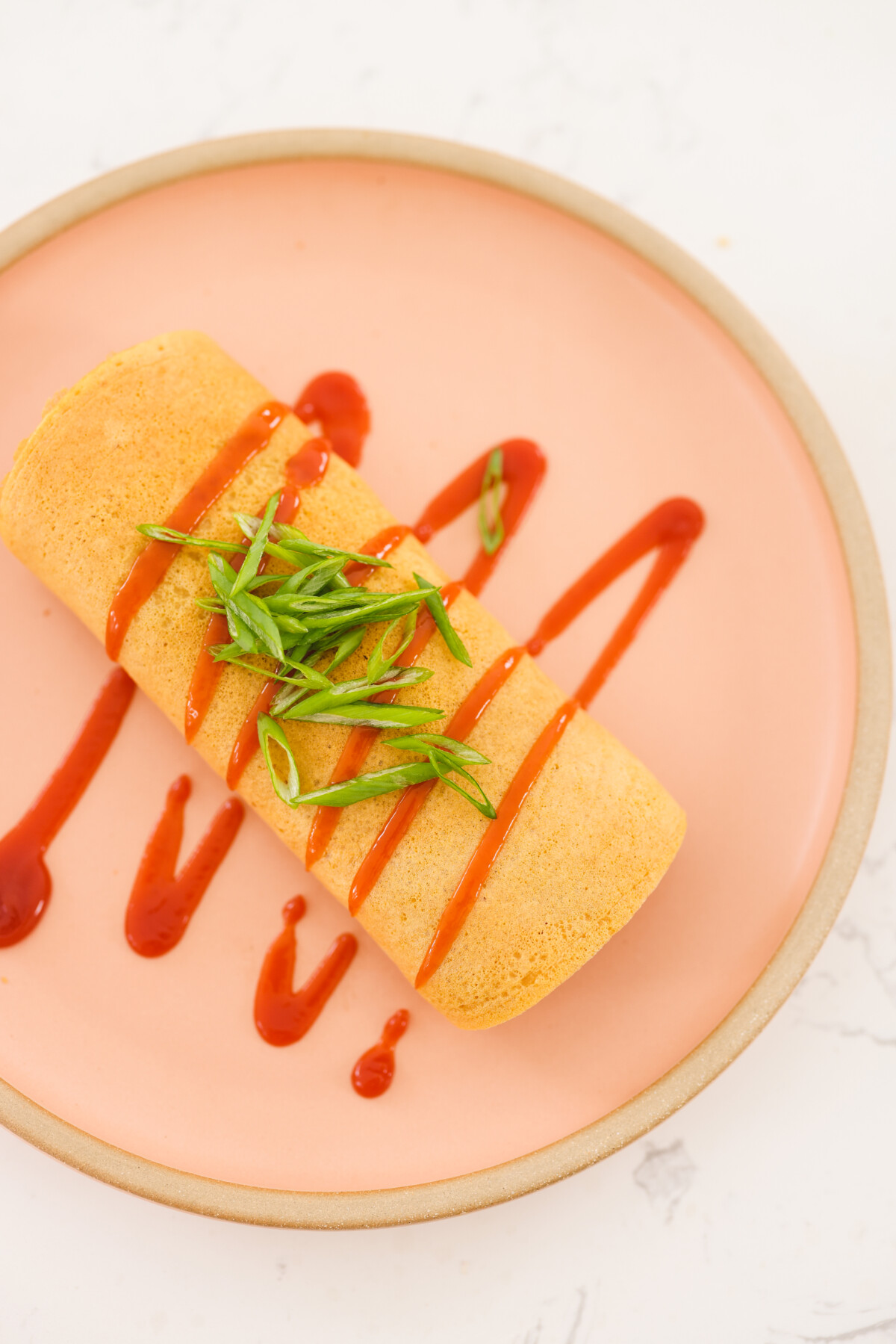 vegan omurice recipe drizzled with ketchup and served on a pink plate. 