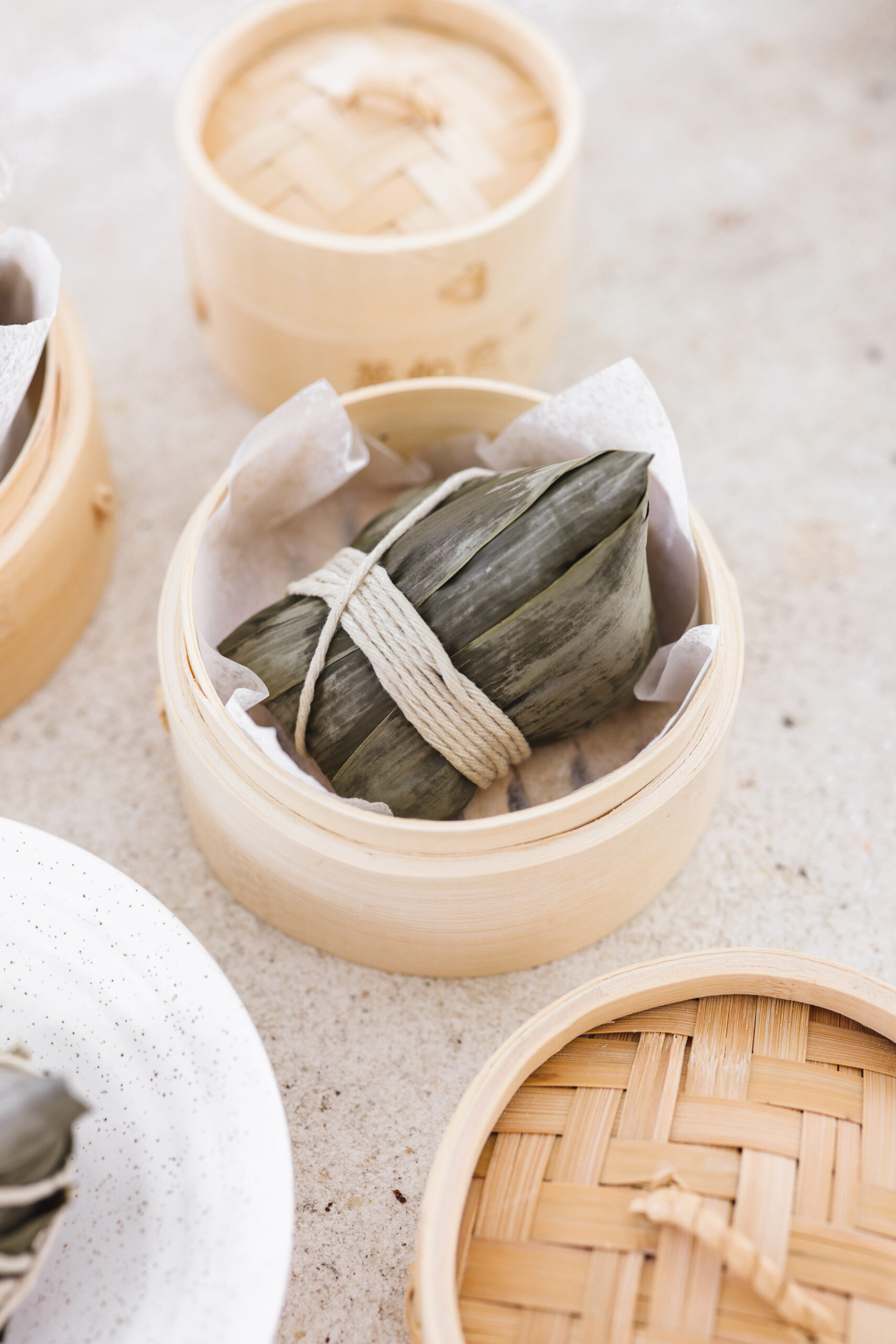 one vegan zongzi wrapped in bamboo and sitting in a wooden bowl