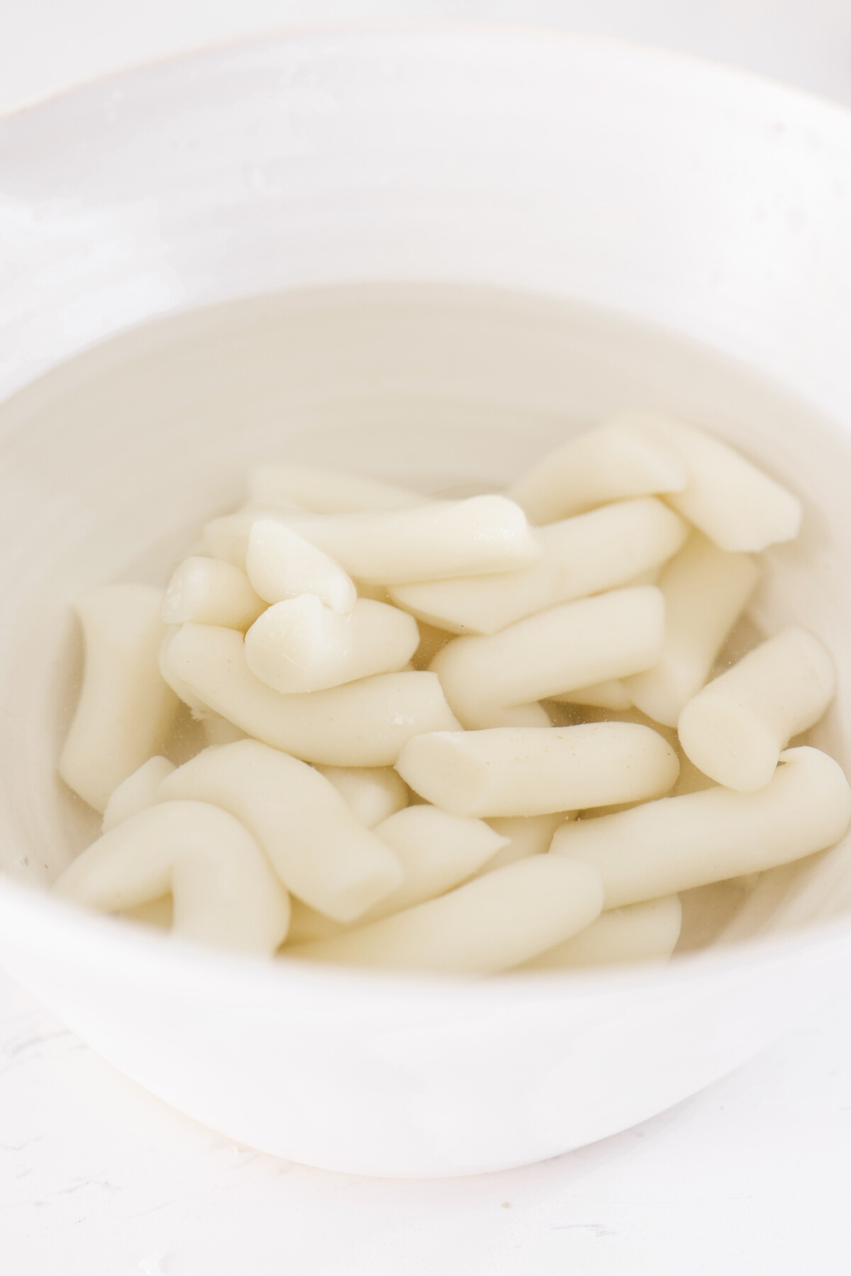 korean rice cakes sitting in a bowl of water