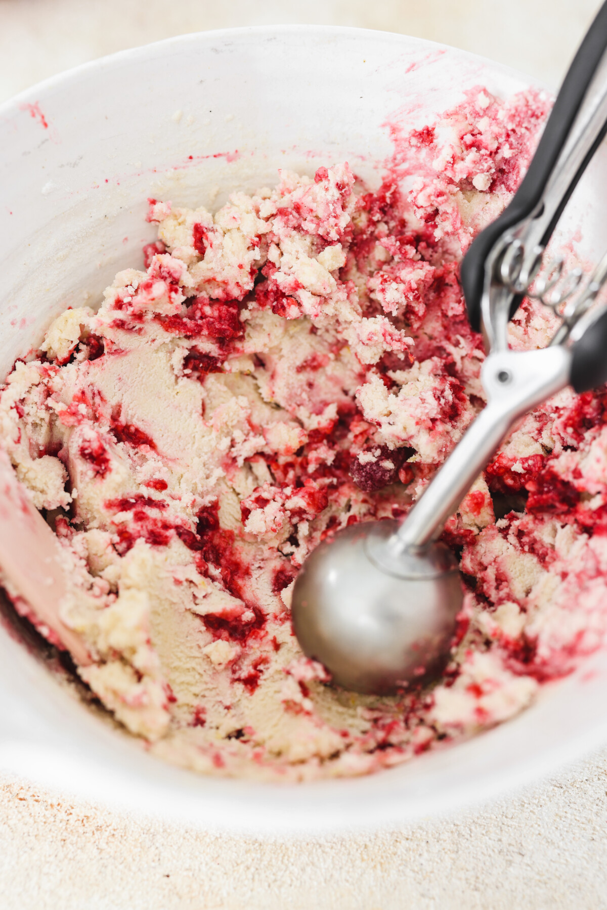 a cookie scoop scooping out a ball of raspberry lemon cookie dough