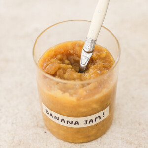 banana jam in a glass jar with a white spoon