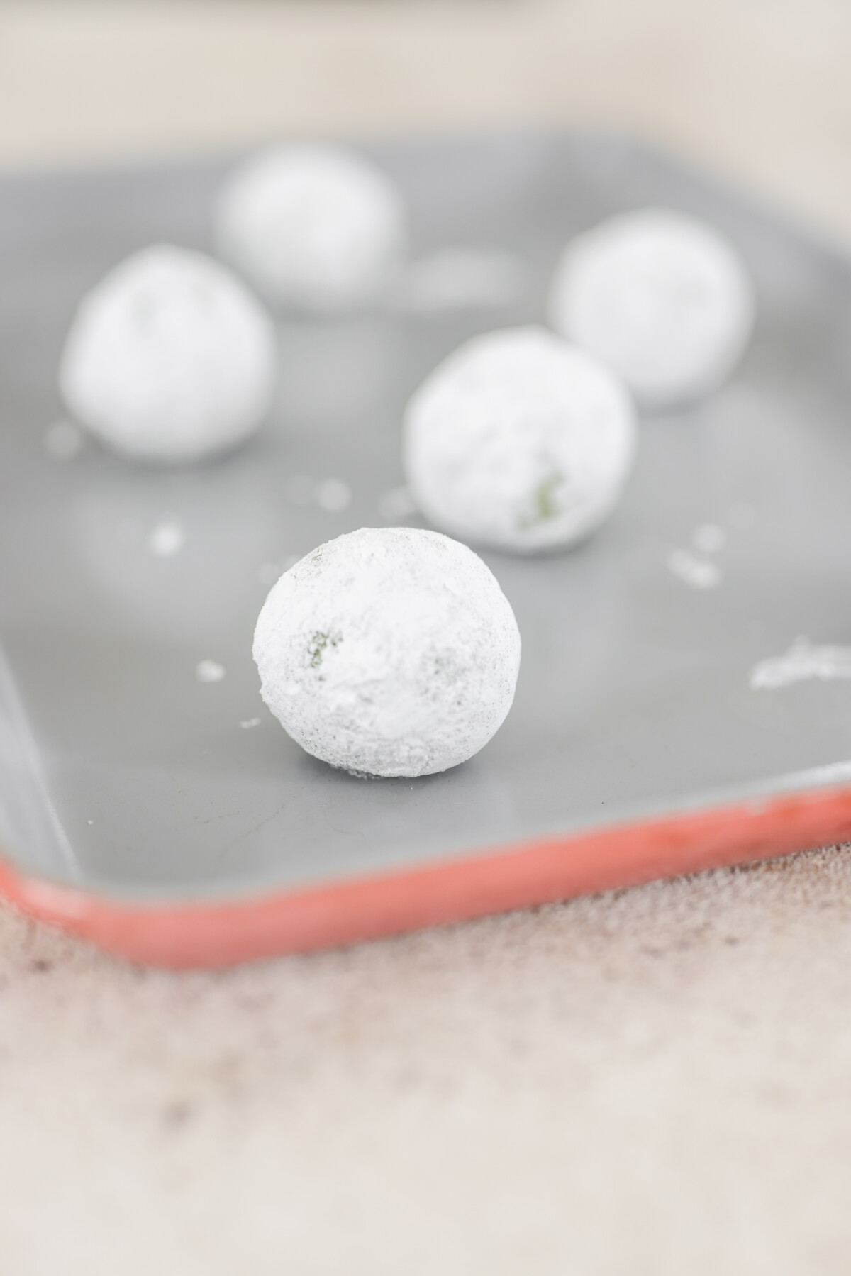 powdered sugar cookie dough balls on a baking sheet 