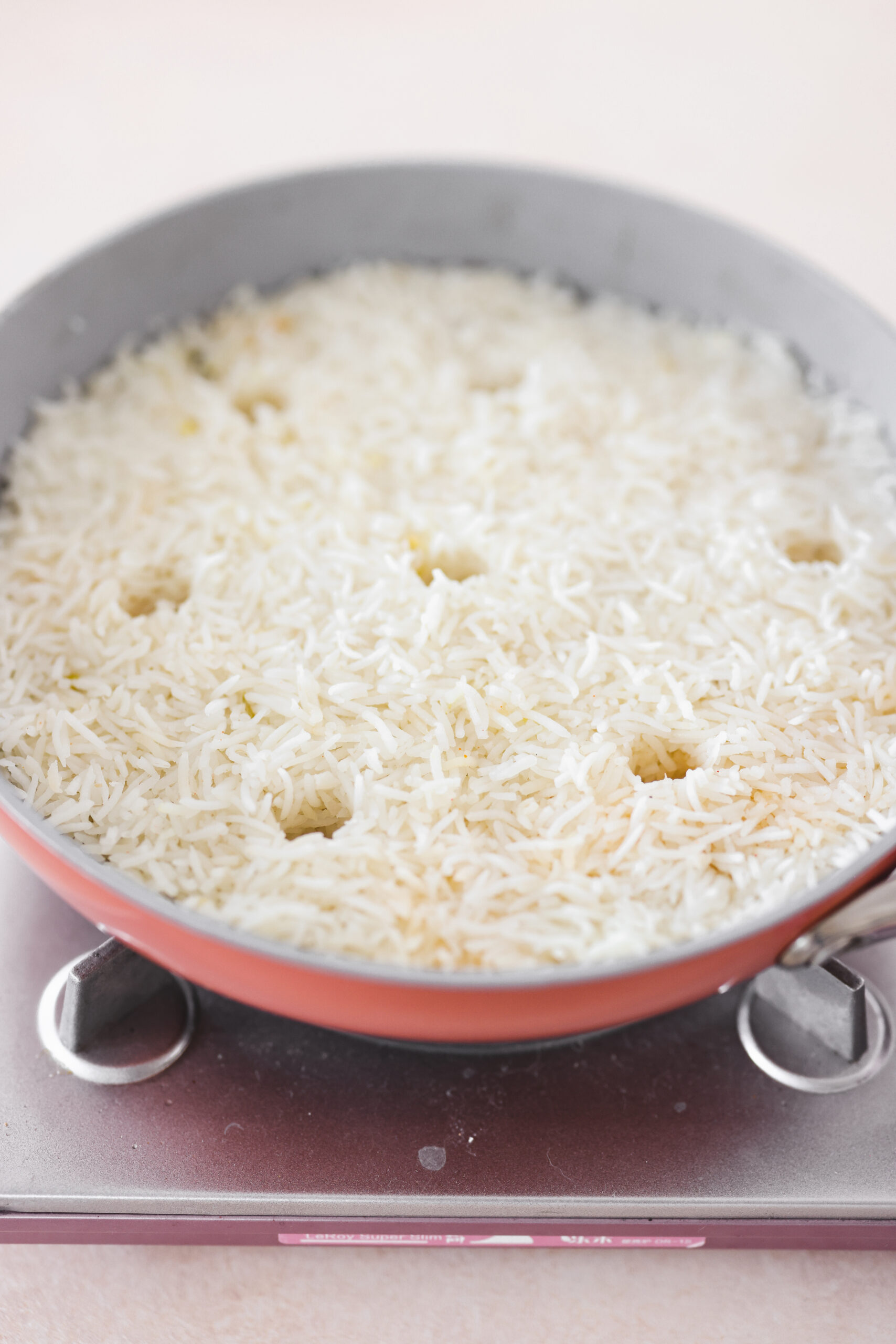 a skillet with holes poked in the rice