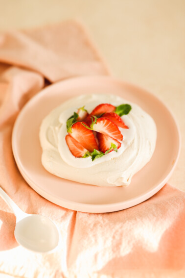 a vegan pavlova topped with strawberries and whipped cream