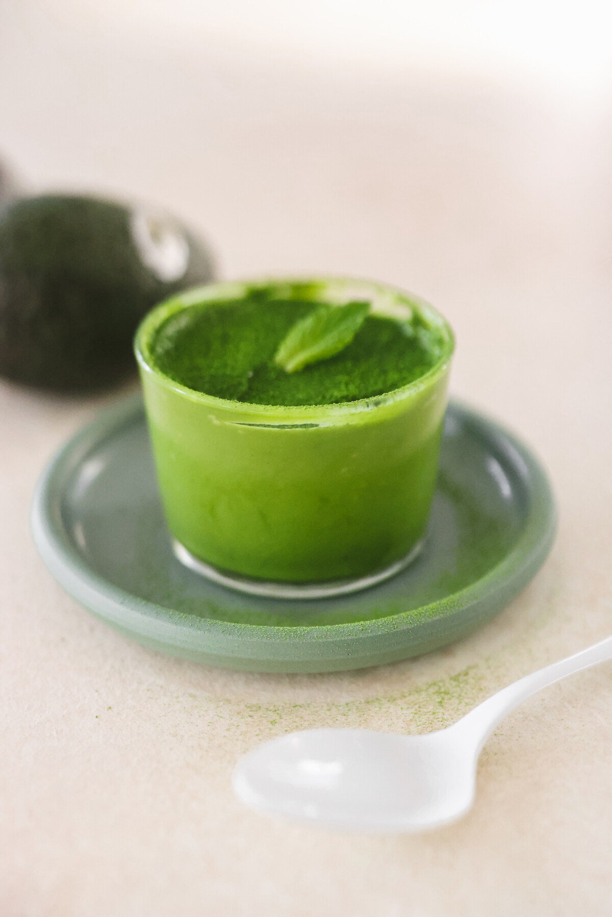 a small glass cup filled with matcha mousse and topped with a sprig of mint. 